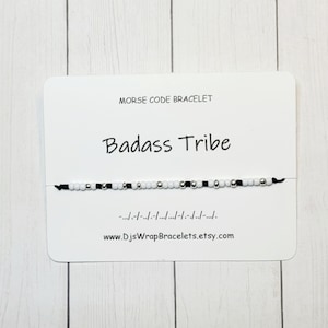 May include: A black and white beaded bracelet with the words "Badass Tribe" and the morse code for the phrase on a white card. The card also includes the website www.DjsWrapBracelets.etsy.com.