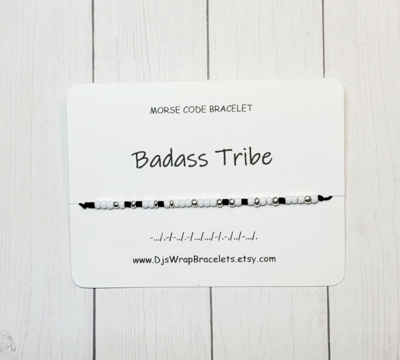 May include: A black and white beaded bracelet with the words "Badass Tribe" and the morse code for the phrase on a white card. The card also includes the website www.DjsWrapBracelets.etsy.com.