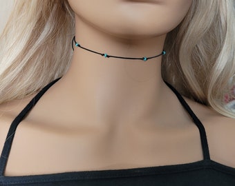 May include: A delicate black choker necklace with small turquoise beads. The necklace is simple and elegant, perfect for everyday wear.