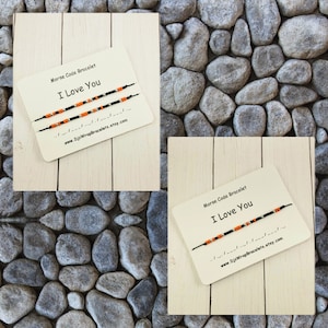 Pu&ograve; includere: Due braccialetti di corda nera con perline arancioni e argentate. I braccialetti compongono "Ti amo" in codice Morse. I braccialetti sono esposti su una carta con il testo "Braccialetto in codice Morse Ti amo" e un indirizzo di sito web.