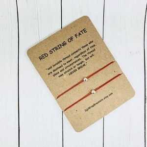 May include: Two red string bracelets with silver beads. The card reads "Red String of Fate" and includes a quote about an invisible thread connecting those destined to meet.