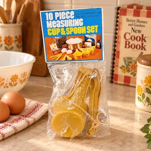 Peut inclure: Un ensemble de 10 tasses et cuillères à mesurer dans un sac en plastique transparent avec une carte d'en-tête bleue et blanche. Le texte indique 10 Piece MEASURING CUP & SPOON SET U.S. STANDARD and METRIC milliliters. Ustensiles en plastique jaune.