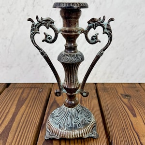 May include: A white ceramic mug with a black handle and the text "But First, Coffee" in a black, handwritten-style font. The mug is on a white surface.