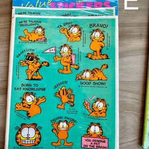 K&ouml;nnte beinhalten: Ein Bogen Garfield-Aufkleber mit verschiedenen Bildern der orangefarbenen Katze mit verschiedenen Spr&uuml;chen. Die Spr&uuml;che lauten: "Wir reden von 'exzellent'!", "Smart City!", "Geboren, um Wissen zu essen", "Ta Dah!", "Bravo!", "Yeeeeeees!", "Gute Show!", "Encore! Encore!" und "Du verdienst einen Klaps auf den Kopf!"
