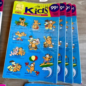 K&ouml;nnte beinhalten: Vier Packungen Garfield Kids Sticker, jede Packung enth&auml;lt vier B&ouml;gen mit Stickern. Die Sticker zeigen Garfield in verschiedenen Posen, darunter beim Surfen, Baseballspielen und mit einem Ballon. Die Packungen sind blau und gelb mit dem Text "Kids Sticker" und "99 Cent" bedruckt.