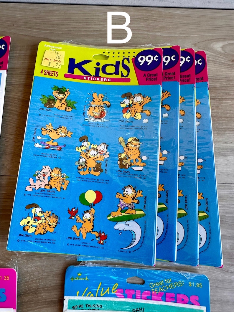 K&ouml;nnte beinhalten: Vier Packungen Garfield Kids Sticker, jede Packung enth&auml;lt vier B&ouml;gen mit Stickern. Die Sticker zeigen Garfield in verschiedenen Posen, darunter beim Surfen, Baseballspielen und mit einem Ballon. Die Packungen sind blau und gelb mit dem Text "Kids Sticker" und "99 Cent" bedruckt.