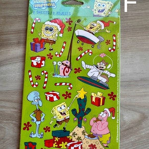 K&ouml;nnte beinhalten: Eine gr&uuml;ne und gelbe Sticker-Tafel mit Figuren aus der Zeichentrickserie SpongeBob Schwammkopf. Die Tafel enth&auml;lt eine Vielzahl von festlichen Stickern, darunter SpongeBob, Patrick, Thadd&auml;us und Sandy. Der Text "SpongeBob SquarePants" und "Stickety-Doo-Da" ist auf der Tafel gedruckt.