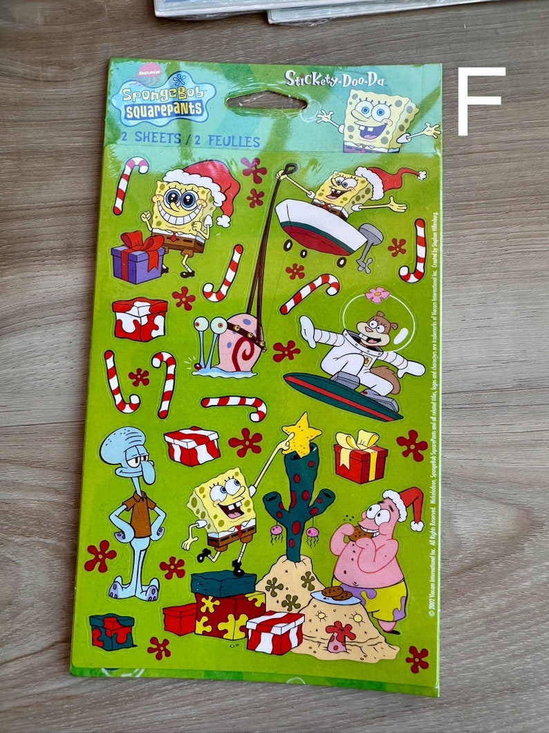 K&ouml;nnte beinhalten: Eine gr&uuml;ne und gelbe Sticker-Tafel mit Figuren aus der Zeichentrickserie SpongeBob Schwammkopf. Die Tafel enth&auml;lt eine Vielzahl von festlichen Stickern, darunter SpongeBob, Patrick, Thadd&auml;us und Sandy. Der Text "SpongeBob SquarePants" und "Stickety-Doo-Da" ist auf der Tafel gedruckt.