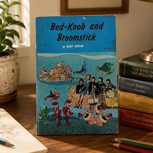 May include: A vintage paperback book titled Bed-Knob and Broomstick by Mary Norton with a blue cover featuring a whimsical underwater illustration of a person sitting on a bed surrounded by anthropomorphic fish and the text TX 2276.