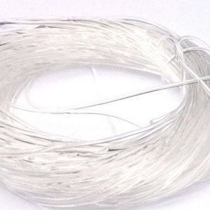 May include: A spool of clear, thin, white string. The string is wound tightly around itself, forming a circle.
