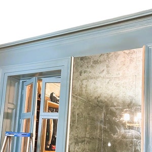 May include: A blue painted door with a glass pane and a mirror behind it. The door is open and a ladder is visible in the doorway.