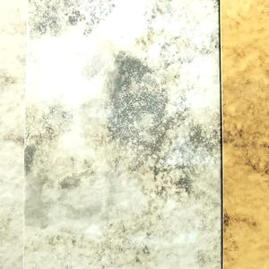 May include: Three rectangular glass panels featuring an antique mirror finish. The left panel is light cream, the center panel is silver with dark mottled oxidation, and the right panel is a warm golden yellow with dark brown distressed patches.