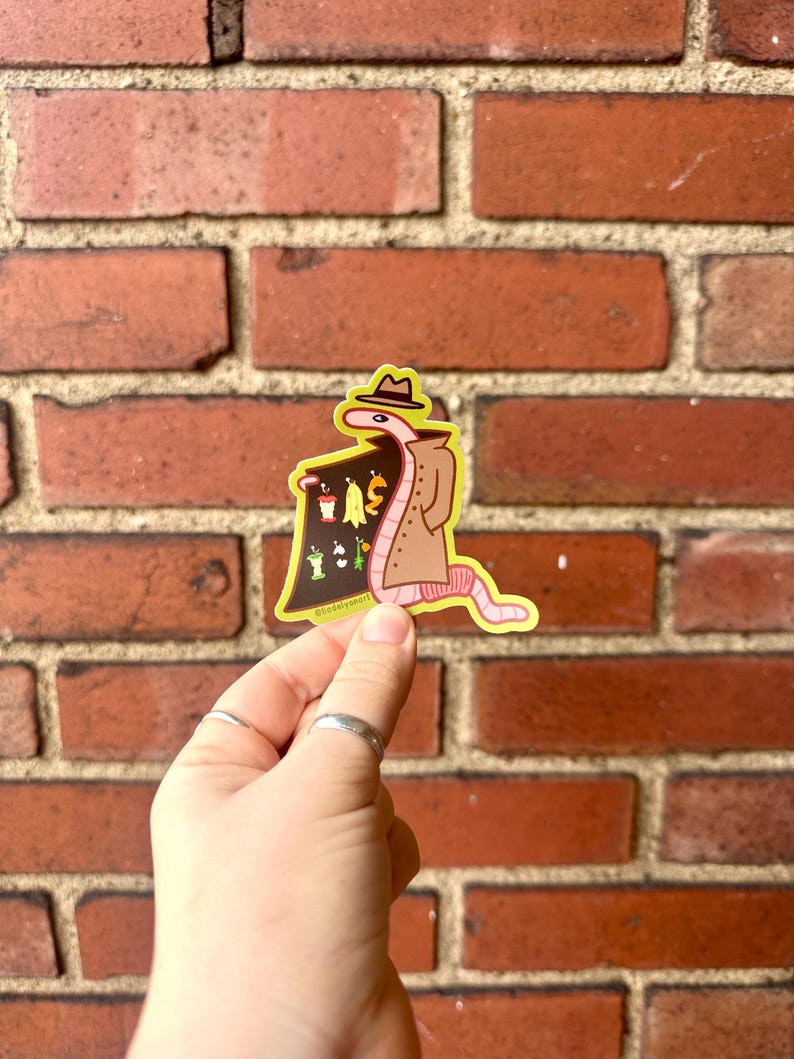 May include: A sticker of a cartoon worm wearing a trench coat and a hat, holding a sign that says "Worms for Sale". The sign has a variety of worms on it, including a red worm, a green worm, a yellow worm, and a brown worm.