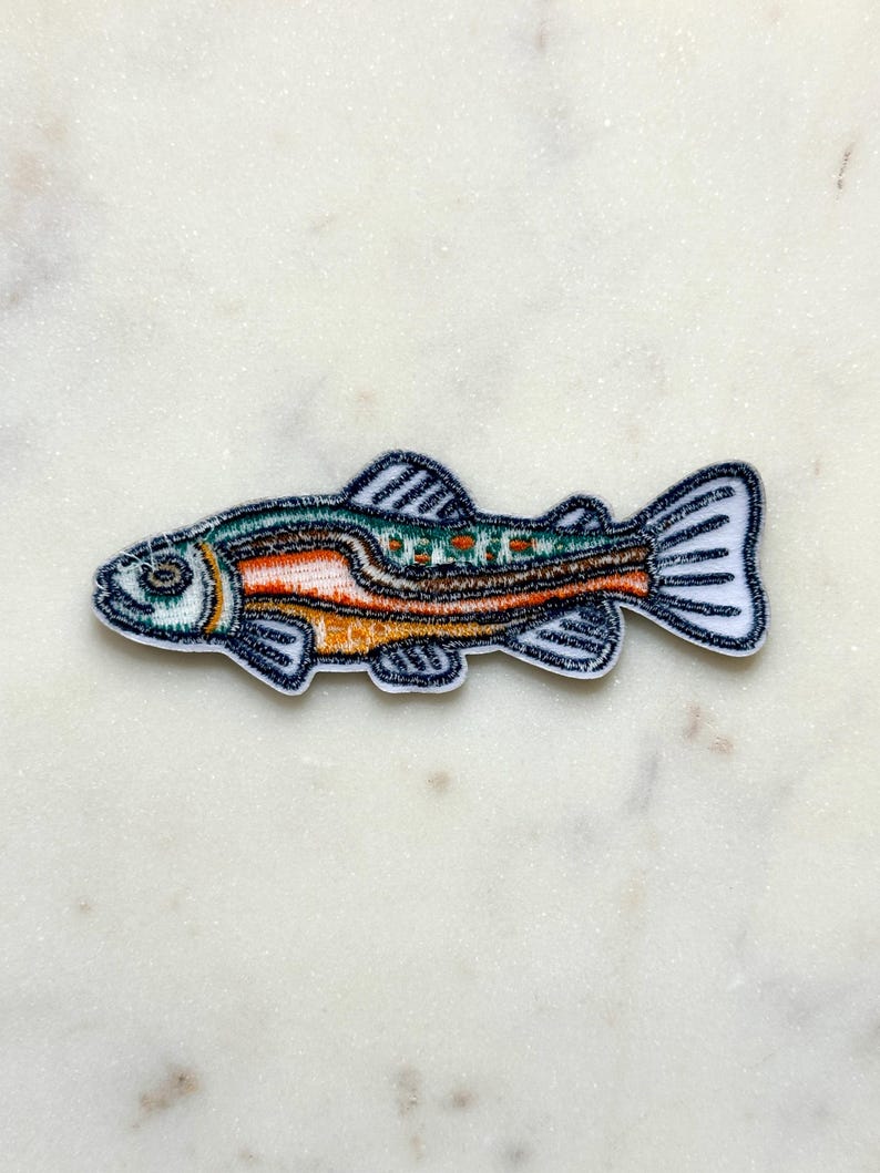 Pu&ograve; includere: Toppa ricamata a forma di pesce. Il pesce ha un contorno bianco ed &egrave; dettagliato con colori arancione, verde e marrone. Le pinne e la coda del pesce sono delineate con un filo blu scuro.