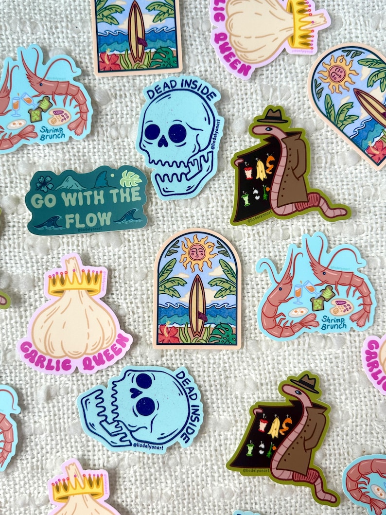 May include: A collection of colorful stickers featuring various designs, including a skull with the text "Dead Inside", a garlic with a crown and the text "Garlic Queen", a worm in a trench coat, and a shrimp with the text "Shrimp Brunch".