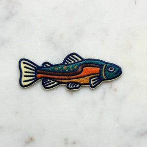 Pu&ograve; includere: Toppa ricamata con un design di pesce colorato. Il pesce ha una testa blu, un corpo arancione e marrone e una coda e pinne color crema. La toppa &egrave; bordata di blu navy.
