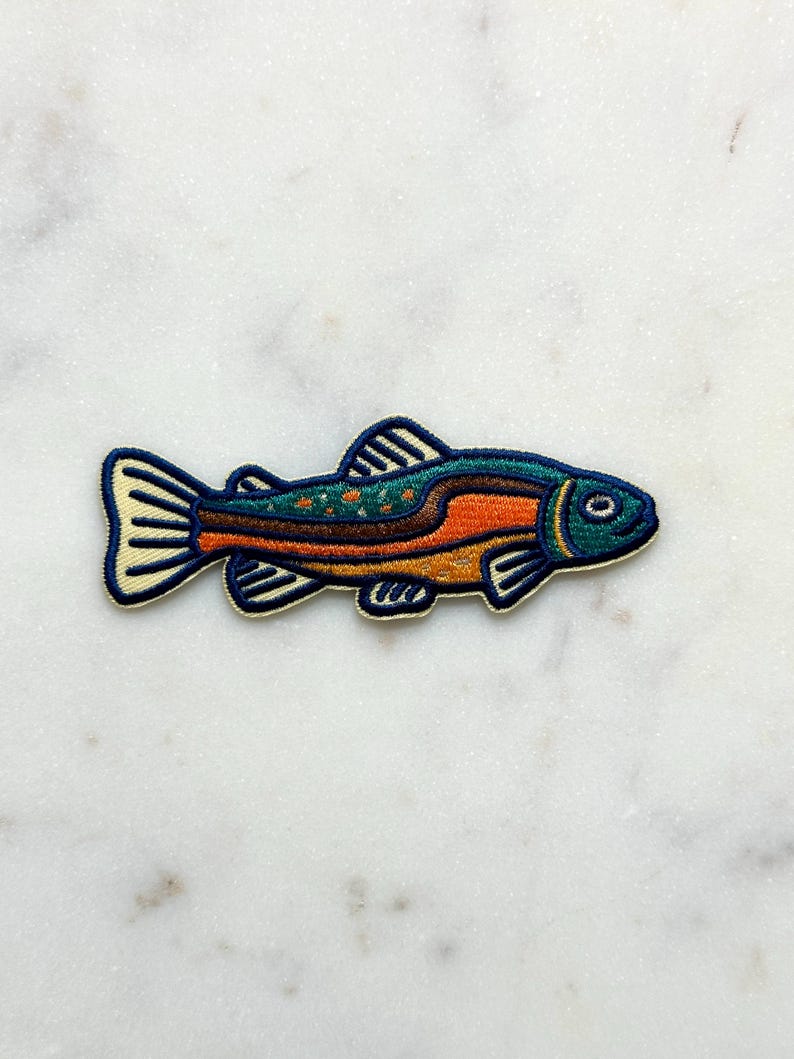 Pu&ograve; includere: Toppa ricamata con un design di pesce colorato. Il pesce ha una testa blu, un corpo arancione e marrone e una coda e pinne color crema. La toppa &egrave; bordata di blu navy.