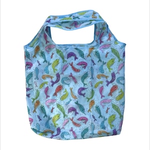 Op de afbeelding: Een lichtblauwe herbruikbare boodschappentas met een kleurrijk garnalenpatroon. De tas heeft een herhalend ontwerp van garnalen in verschillende kleuren, waaronder roze, groen, oranje en paars, tegen een lichtblauwe achtergrond. De tas heeft een handvat om te dragen.