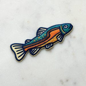 Pu&ograve; includere: Toppa ricamata a forma di pesce. Il pesce ha la testa blu, il corpo arancione e pois turchesi. Le pinne e la coda sono bordate di color crema. La toppa &egrave; progettata per essere stirata o cucita sul tessuto.