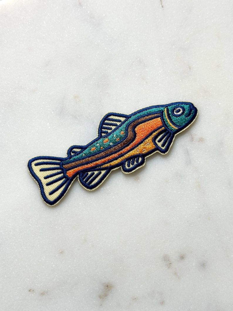 Pu&ograve; includere: Toppa ricamata a forma di pesce. Il pesce ha la testa blu, il corpo arancione e pois turchesi. Le pinne e la coda sono bordate di color crema. La toppa &egrave; progettata per essere stirata o cucita sul tessuto.