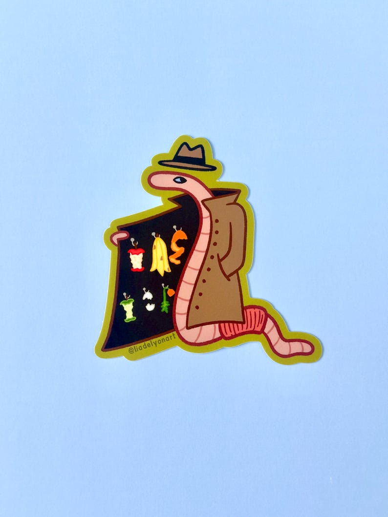 May include: A pink worm wearing a brown trench coat and a brown fedora hat, holding a black sign with the text "@liadelvonart" and various colorful fruits and vegetables on it.