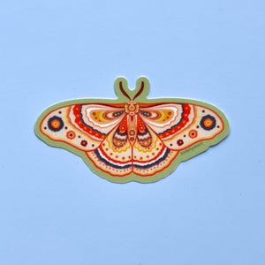 May include: A colorful butterfly sticker with intricate details in shades of orange, yellow, red, and blue. The butterfly has a green body and is outlined in black. The sticker has the text "Radilyoart" in the bottom right corner.