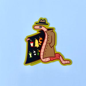 May include: A cartoon worm wearing a brown trench coat and a fedora hat, holding a sign with a variety of fruits and vegetables. The sign says "@liadelvanart".