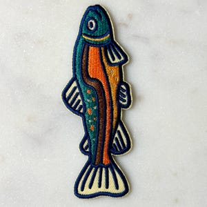 Pu&ograve; includere: Toppa ricamata a forma di pesce. Il pesce ha una testa turchese, un corpo arancione e pinne e coda blu. La toppa &egrave; bordata di color crema.