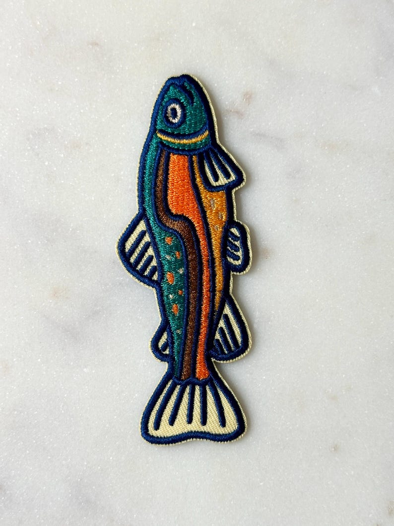 Pu&ograve; includere: Toppa ricamata a forma di pesce. Il pesce ha una testa turchese, un corpo arancione e pinne e coda blu. La toppa &egrave; bordata di color crema.