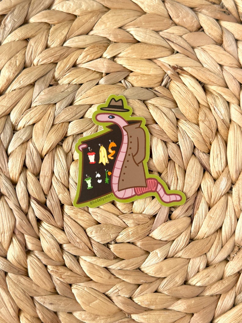 May include: A brown worm wearing a brown trench coat and a brown fedora hat is holding a sign with a variety of fruits and vegetables. The sign is green and has the text "@hadelvyoart" on the bottom.