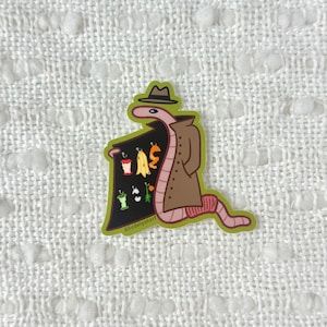 May include: A cartoon worm wearing a brown trench coat and a hat, holding a sign with a variety of fruits and vegetables. The sign is black with white text that says "@hadleysoonart".