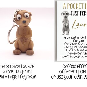 May include: A brown meerkat keyring with large eyes and a silver ring. Beside it is a white card with a meerkat illustration and the text "A POCKET HUG JUST FOR YOU". The card also includes the text "A special pocket hug for you..."