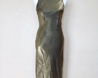 May include: A long, sleeveless, gold metallic dress with a simple, straight neckline. The dress is made of a silky fabric and has a slight sheen.