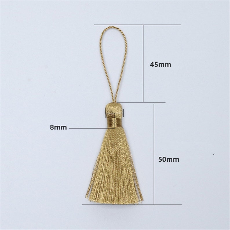 Puede incluir: Un borl&oacute;n dorado con un lazo en la parte superior, que mide 8 mm de ancho y 50 mm de largo. El borl&oacute;n tiene 45 mm de alto.