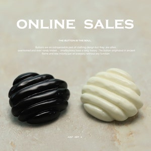 Puede incluir: Dos botones redondos, uno negro y otro blanco, con un diseño texturizado y acanalado. Los botones están sobre un fondo blanco con el texto "ONLINE SALES" y "THE BUTTON IS THE SOUL" encima.