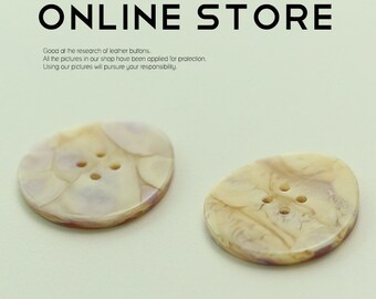 May include: Two beige and brown shell buttons with four holes each. The buttons have a marbled pattern.