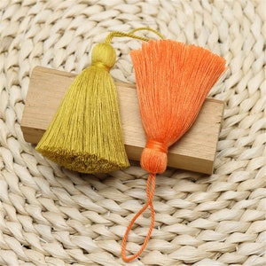 Può includere: Due nappine, una gialla e una arancione, con un anello all'estremità della nappina arancione.
