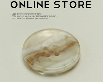 May include: A close-up of a white and brown marbled button with four holes. The button is round and has a smooth surface.