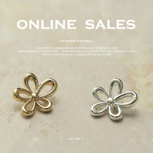 Könnte beinhalten: Zwei blütenförmige Knöpfe, einer golden und einer silbern, vor einem weißen Hintergrund. Die Knöpfe sind klein und zart, mit einem einfachen Design. Der Text "THE BUTTON IS THE SOUL" ist über den Knöpfen sichtbar.