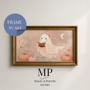 Può includere: Stampa incorniciata con un fantasmino che legge un libro, con una morbida tavolozza di colori rosa e pesca. L'opera d'arte include zucche, fiori e una luna crescente. La cornice è di colore oro caldo. Il testo "FRAME TV ART" è in un cerchio blu.