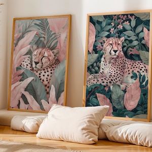 May include: Two framed art prints featuring cheetahs in a jungle setting. One print shows a cheetah resting among pink and green leaves. The other print depicts a cheetah lying down amidst lush foliage, with pink flowers and leaves.