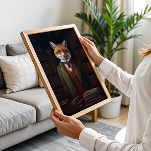 Person holding framed Victorian fox artwork in elegant neutral living room with natural light and cozy decor
