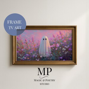 May include: A framed digital art print featuring a whimsical ghost in a field of purple and pink flowers. The artwork has a soft, dreamy quality, with a gold-colored frame. The text "FRAME TV ART" is in a blue circle in the upper left corner.
