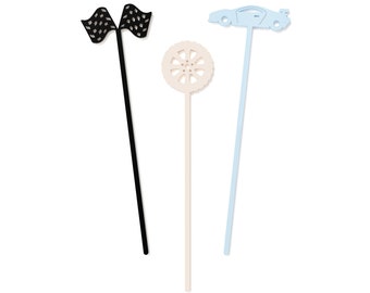 May include: Three black, white, and blue paper party picks with a checkered flag, a car, and a tire design. The picks are on a white background.