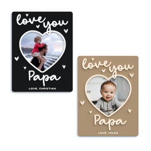 May include: Two brown and black photo cards with a white heart-shaped frame. The cards have the text "love you" and "Papa" in white script. The cards have a photo of a child with their father and a photo of a baby.
