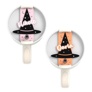 May include: Two white ceramic hooks with a black witch hat and a name on each. The hook on the left has a pink background with the name "Nikole" and the hook on the right has an orange background with the name "Darla".