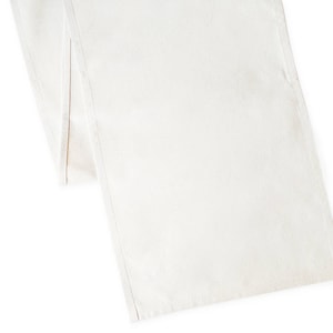 May include: A plain white table runner made of cotton fabric. The runner is 14 inches wide and 70 inches long.