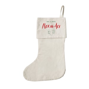 May include: A white Christmas stocking with a green and red embroidered design of mittens and the text "MR. & MRS. Alexander".