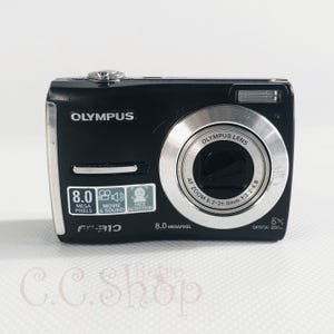 May include: Black Olympus digital camera with silver accents. Features include 8.0 megapixels, movie and sound detection, and a 5x optical zoom. The camera has the model number FR10 and the Olympus lens has an AF zoom of 6.2-31.0mm.