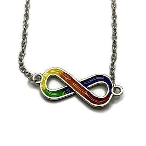 Puede incluir: Un collar de cadena de plata con un colgante en forma de símbolo de infinito. El colgante está coloreado en un patrón de arcoíris con rojo, naranja, amarillo, verde, azul y morado.